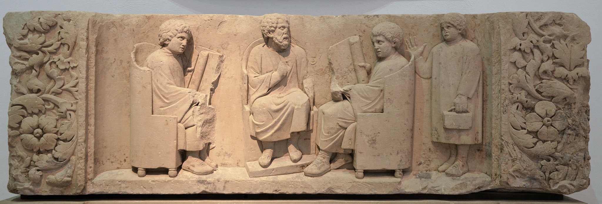 Un maître et trois élèves (discipuli). Relief funéraire découvert à Neumagen, près de Trèves, vers 180–185 apr. J.-C. Les deux élèves assis tiennent un rouleau ouvert, tandis qu’un plus jeune arrive avec des tablettes de cire. Rheinisches Landesmuseum Trier. (Photo: Carole Raddato, CC BY-NC-SA.)